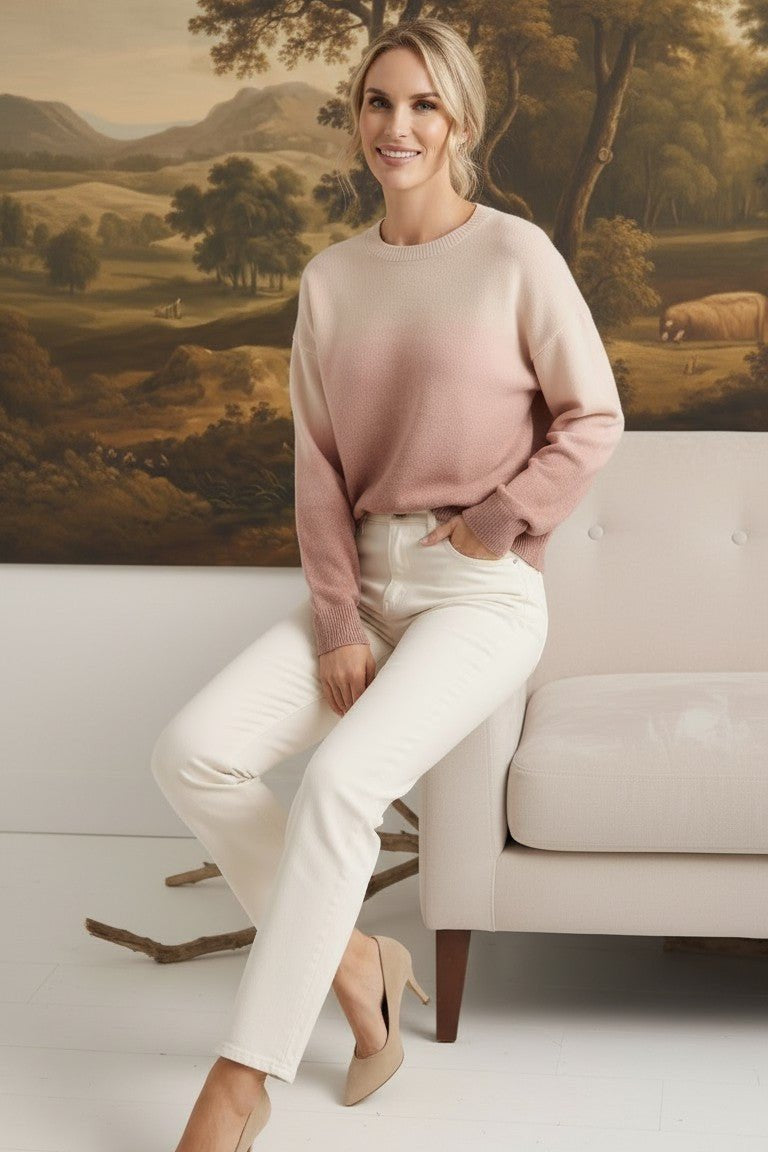 graced The Joan Gradient Sweater in soft pink and cream, worn by a model with white jeans and beige heels.