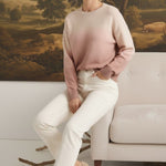 graced The Joan Gradient Sweater in soft pink and cream, worn by a model with white jeans and beige heels.