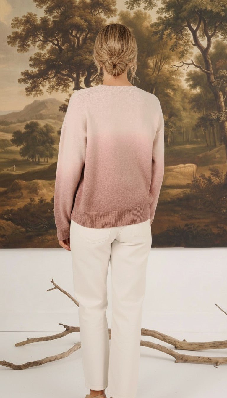graced The Joan Gradient Sweater in soft pink ombre worn with white trousers, back view