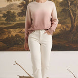 Model wearing a graced Joan gradient sweater in soft pink and cream tones with white jeans in a studio setting.