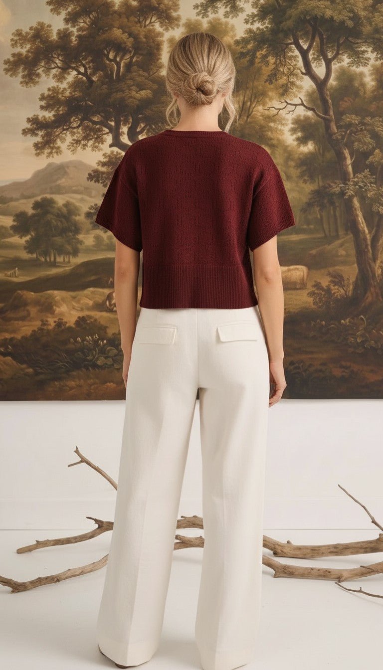 graced Jocelyn button up knit top in burgundy worn by a model with white trousers, back view