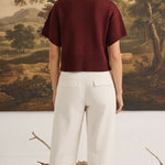 graced Jocelyn button up knit top in burgundy worn by a model with white trousers, back view