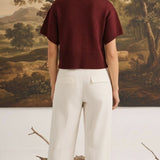 graced Jocelyn button up knit top in burgundy worn by a model with white trousers, back view