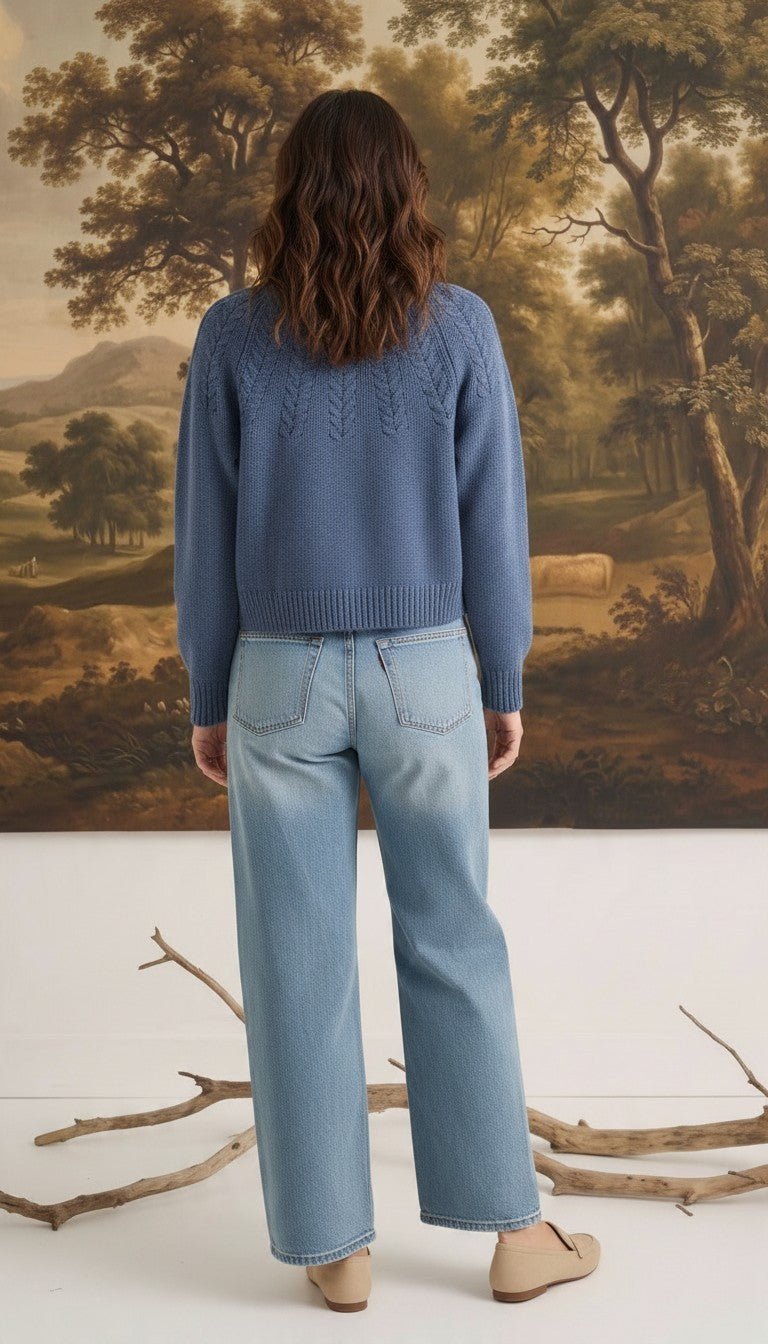 Back view of a woman wearing a graced Kaitlyn sailor sweater in denim blue with knit detailing paired with jeans