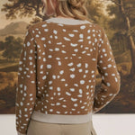 Back view of a woman wearing a graced Kathy brown knit sweater with a white deer pattern and ribbed trim