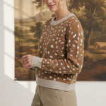 graced Kathy sweater in brown with white deer pattern, featuring a crew neck and ribbed trim, worn by a blonde model