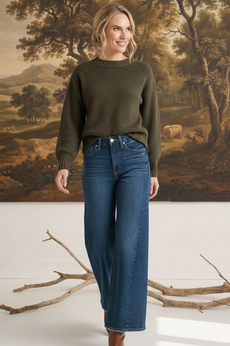 graced The Lily wide leg jeans in dark blue denim paired with an olive green sweater on a model