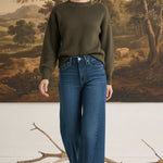 graced The Lily wide leg jeans in dark blue denim paired with an olive green sweater on a model