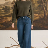 graced The Lily wide leg jeans in dark blue denim paired with an olive green sweater on a model
