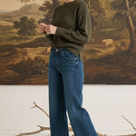graced model wearing The Lily high-waisted wide leg blue denim jeans with a dark green sweater and brown boots