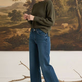 graced model wearing The Lily high-waisted wide leg blue denim jeans with a dark green sweater and brown boots