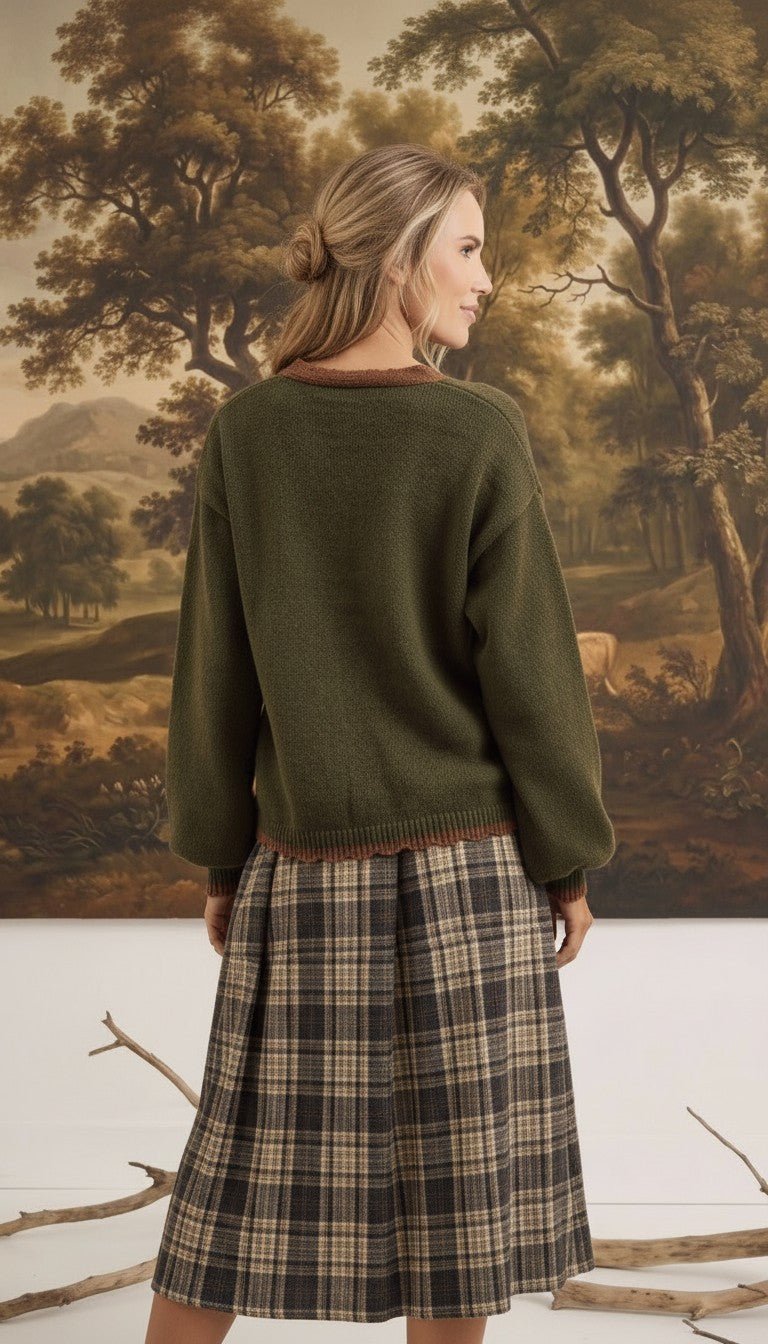 graced The Lola Pocket Detail Cardigan in olive green with brown trim, worn by a woman with a plaid skirt