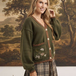 graced The Lola olive green knit cardigan with brown trim, button front, and floral embroidered pockets on a model