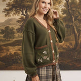 graced The Lola olive green knit cardigan with brown trim, button front, and floral embroidered pockets on a model