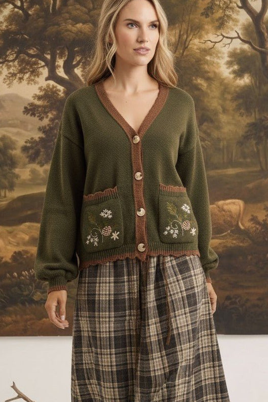 graced Lola cardigan in olive green with floral embroidery on pockets, worn over a plaid skirt by a blonde model