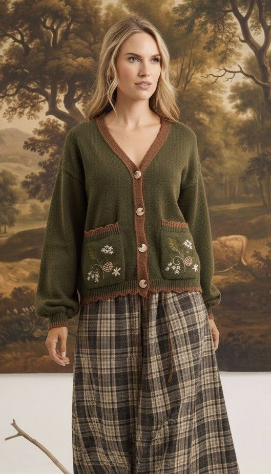 graced Lola cardigan in olive green with floral embroidery on pockets, worn over a plaid skirt by a blonde model