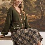 graced The Lola Pocket Detail Cardigan in olive green with floral embroidery, button front, and brown trim.