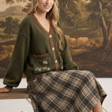 graced The Lola Pocket Detail Cardigan in olive green with floral embroidery, button front, and brown trim.