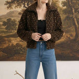 Model wearing a graced brown patterned fleece jacket with a zip-up collar and long sleeves over a black top.