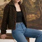 graced Lydia fleece jacket in dark brown with a subtle star pattern, worn by a model sitting on a wooden bench