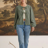 Model wearing graced Madilynne Gingham Top in green with long sleeves, lace trim, and a tie neckline over blue jeans