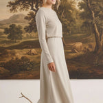 graced Margo wool midi skirt in beige worn by a blonde model with a long-sleeved top against a landscape painting