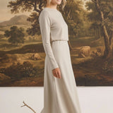 graced Margo wool midi skirt in beige worn by a blonde model with a long-sleeved top against a landscape painting