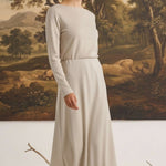 graced The Margo wool midi skirt in beige worn by a blonde model in a long-sleeved matching top against a landscape