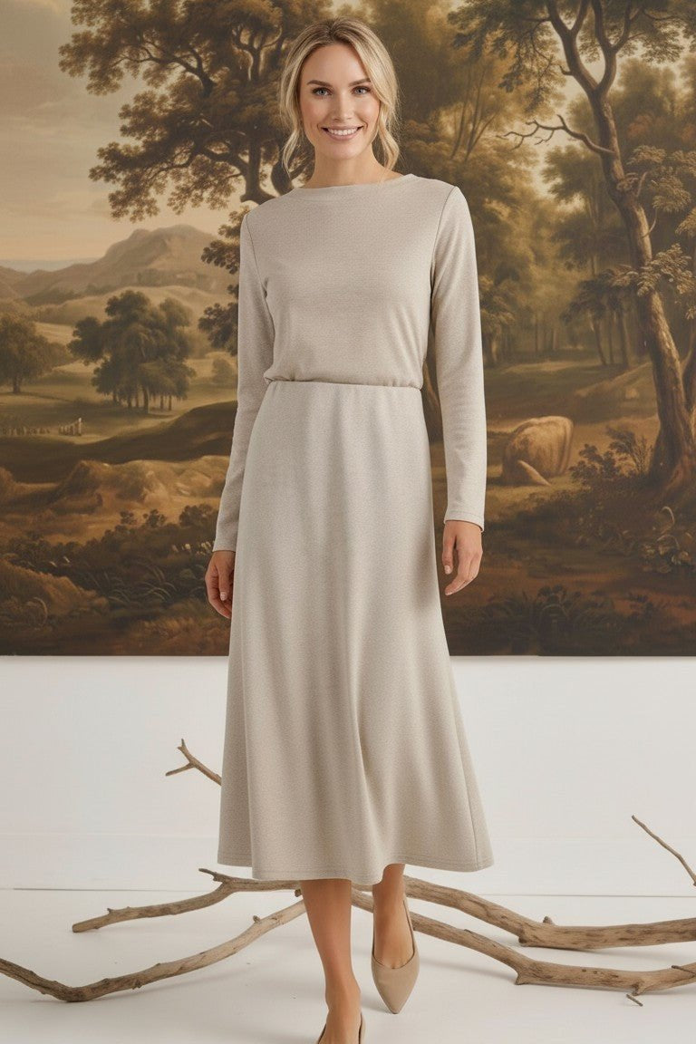 graced model wearing a beige wool-blend midi skirt and long-sleeve top in a studio with a landscape painting backdrop
