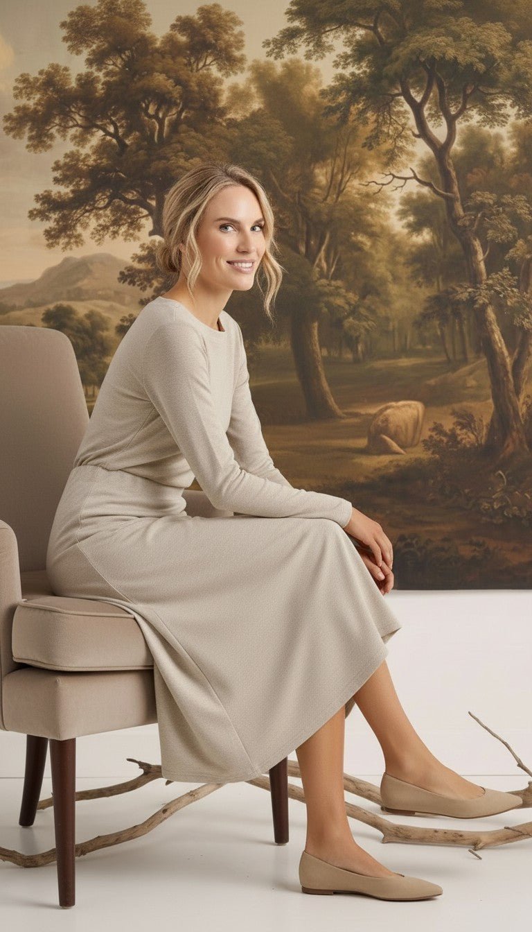 graced Margo wool midi skirt in beige worn by a smiling model sitting on a chair in a classic interior setting