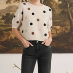 Model wearing a graced beige short-sleeve knit top with multi-color polka dots and a relaxed fit