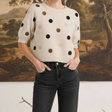 Model wearing a graced beige short-sleeve knit top with multi-color polka dots and a relaxed fit