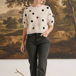 graced Michelle knit top in cream with multi-color polka dots, short sleeves, and relaxed fit worn with dark jeans.