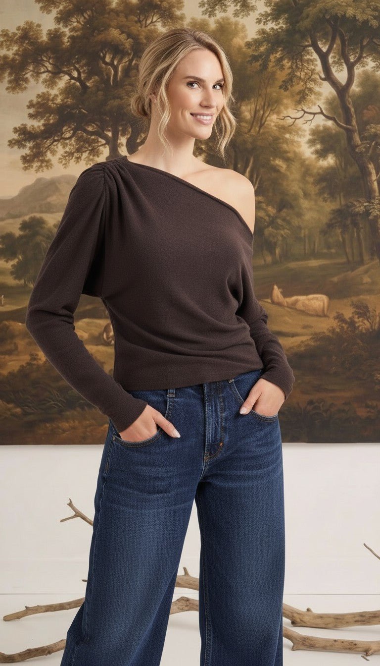 graced chocolate brown off-the-shoulder top with long sleeves and asymmetrical neckline worn with blue jeans
