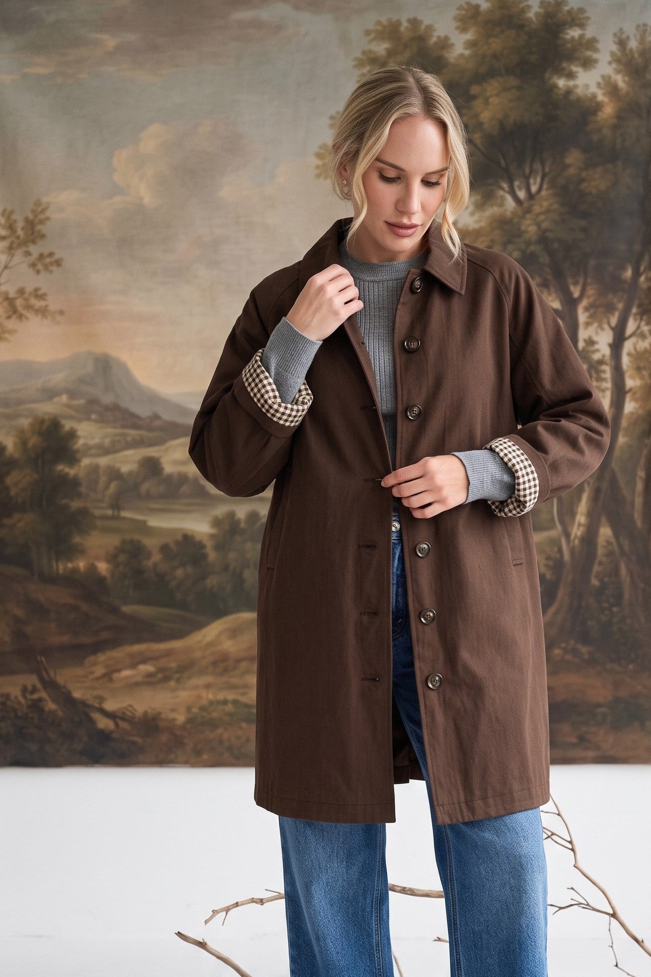 graced The Raven midi trench coat in brown with a classic collar and gingham check lining, worn by a blonde model.