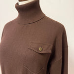 graced brown turtleneck sweater featuring a single chest pocket with a metal button on a mannequin