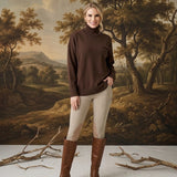 graced Remy brown turtleneck sweater with a chest pocket, worn by a woman with beige riding pants and brown boots
