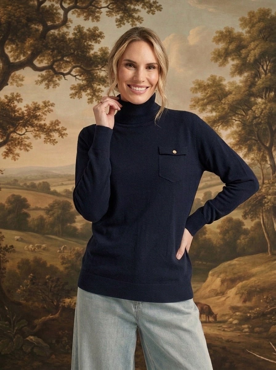 graced Remy navy turtleneck sweater with a single chest pocket, worn by a smiling woman against a landscape backdrop.