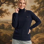 graced Remy navy turtleneck sweater with a single chest pocket, worn by a smiling woman against a landscape backdrop.