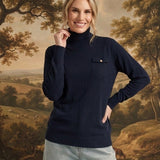 graced Remy navy turtleneck sweater with a single chest pocket, worn by a smiling woman against a landscape backdrop.