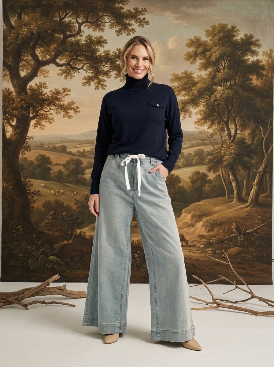 A model wearing the graced navy Remy turtleneck sweater with a chest pocket, paired with wide-leg light wash jeans.