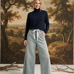 A model wearing the graced navy Remy turtleneck sweater with a chest pocket, paired with wide-leg light wash jeans.