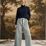 A model wearing the graced navy Remy turtleneck sweater with a chest pocket, paired with wide-leg light wash jeans.