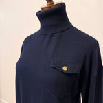 graced navy turtleneck sweater with a single chest pocket and ribbed collar on a mannequin