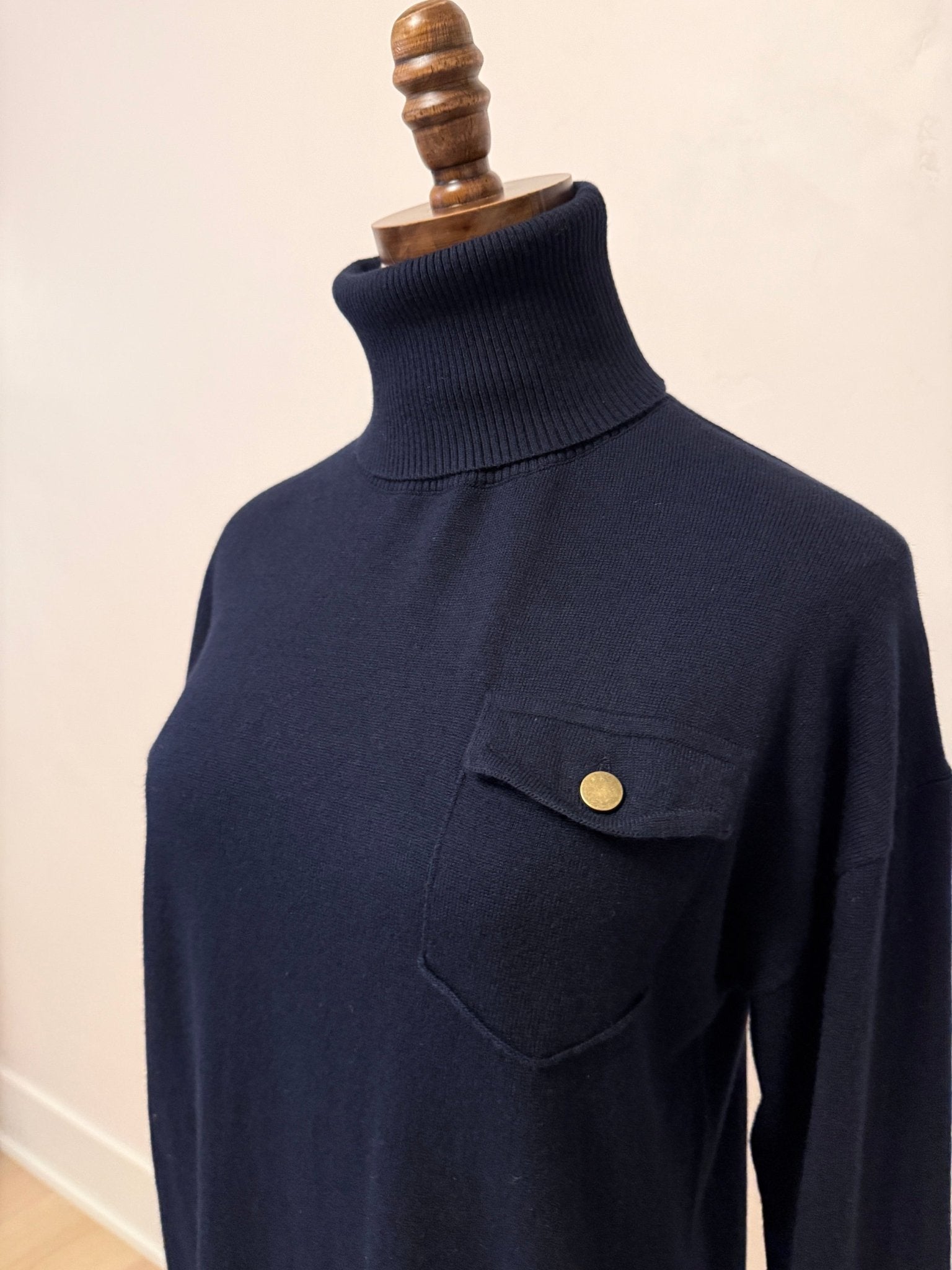 graced navy turtleneck sweater with a single chest pocket and ribbed collar on a mannequin