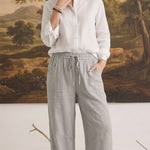 graced The Rita relaxed grey striped pants in a rayon-linen blend with a drawstring waist, worn with a white shirt.