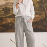 graced The Rita relaxed grey striped pants in a rayon-linen blend with a drawstring waist, worn with a white shirt.