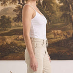 Model wearing graced white fitted nylon-spandex cami with spaghetti straps, side profile view.