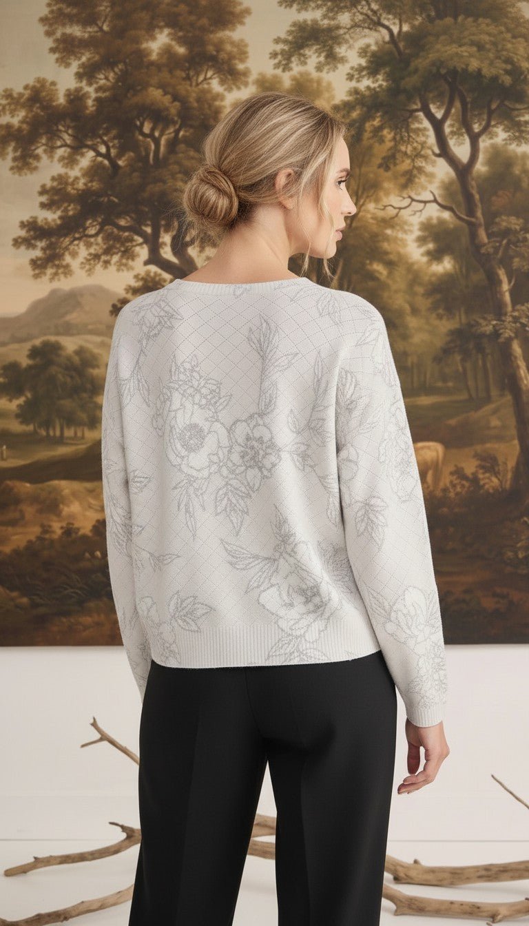 Back view of a woman wearing a graced diamond pointelle floral sweater in a light grey fine gauge knit fabric.