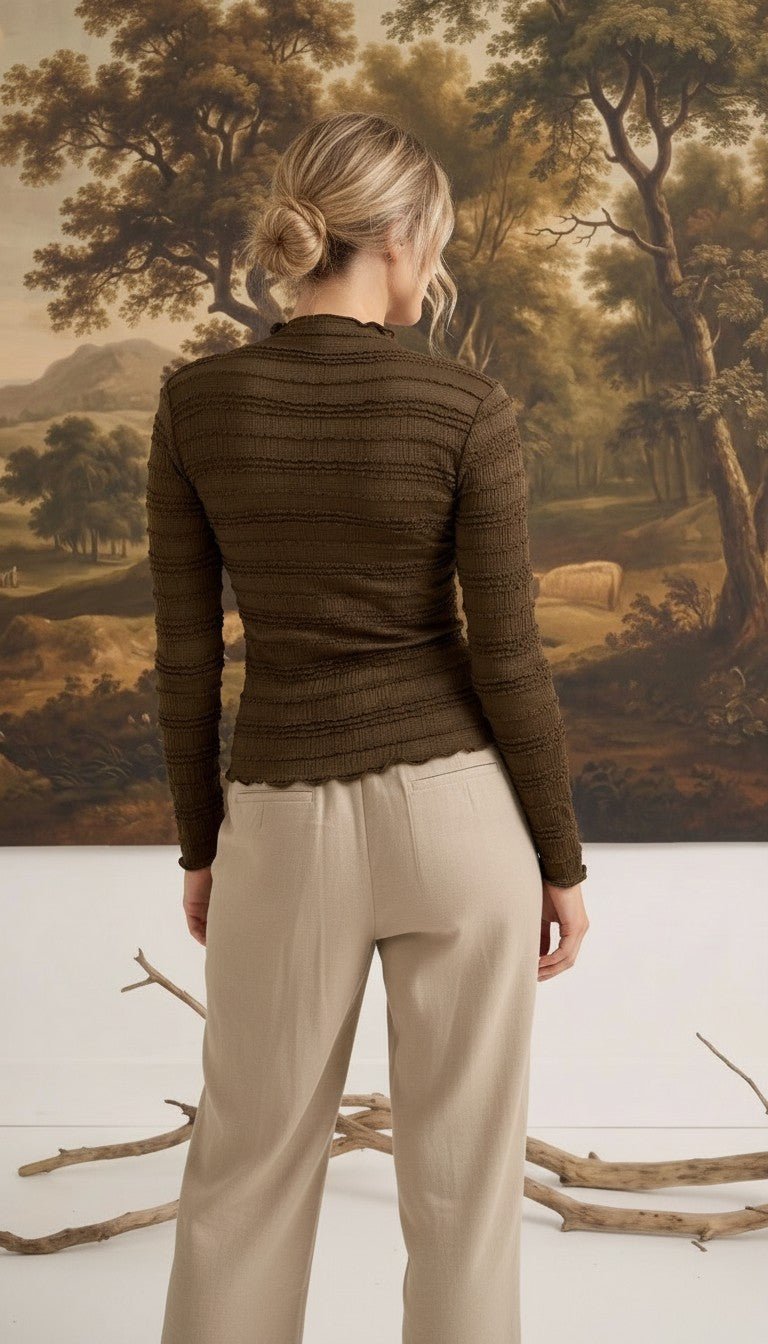 graced The Tatum chocolate brown long sleeve top with textured fabric and lettuce-edge hem worn by a woman